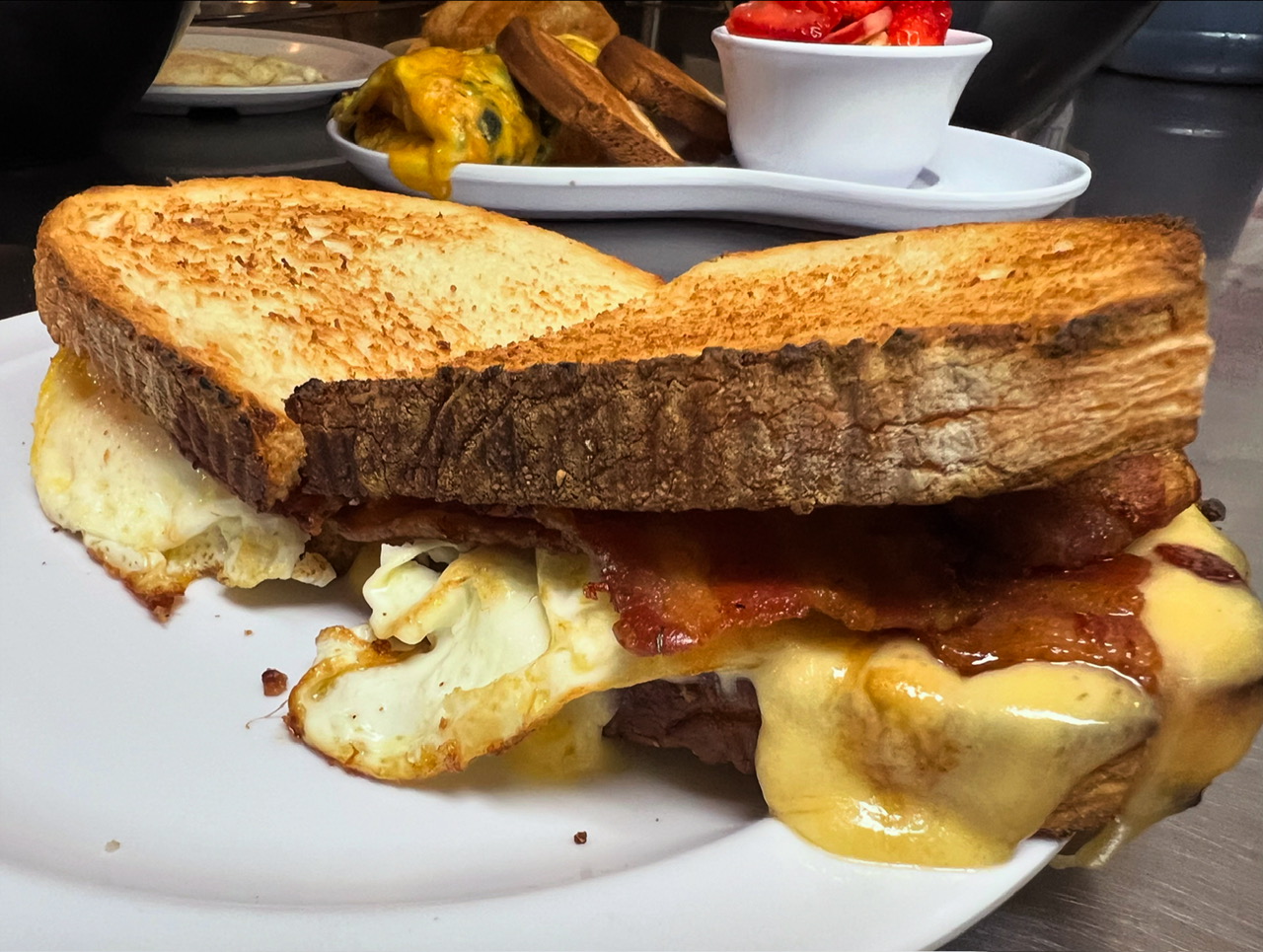 Close-up of a fried egg, bacon and cheese breakfast sandwich