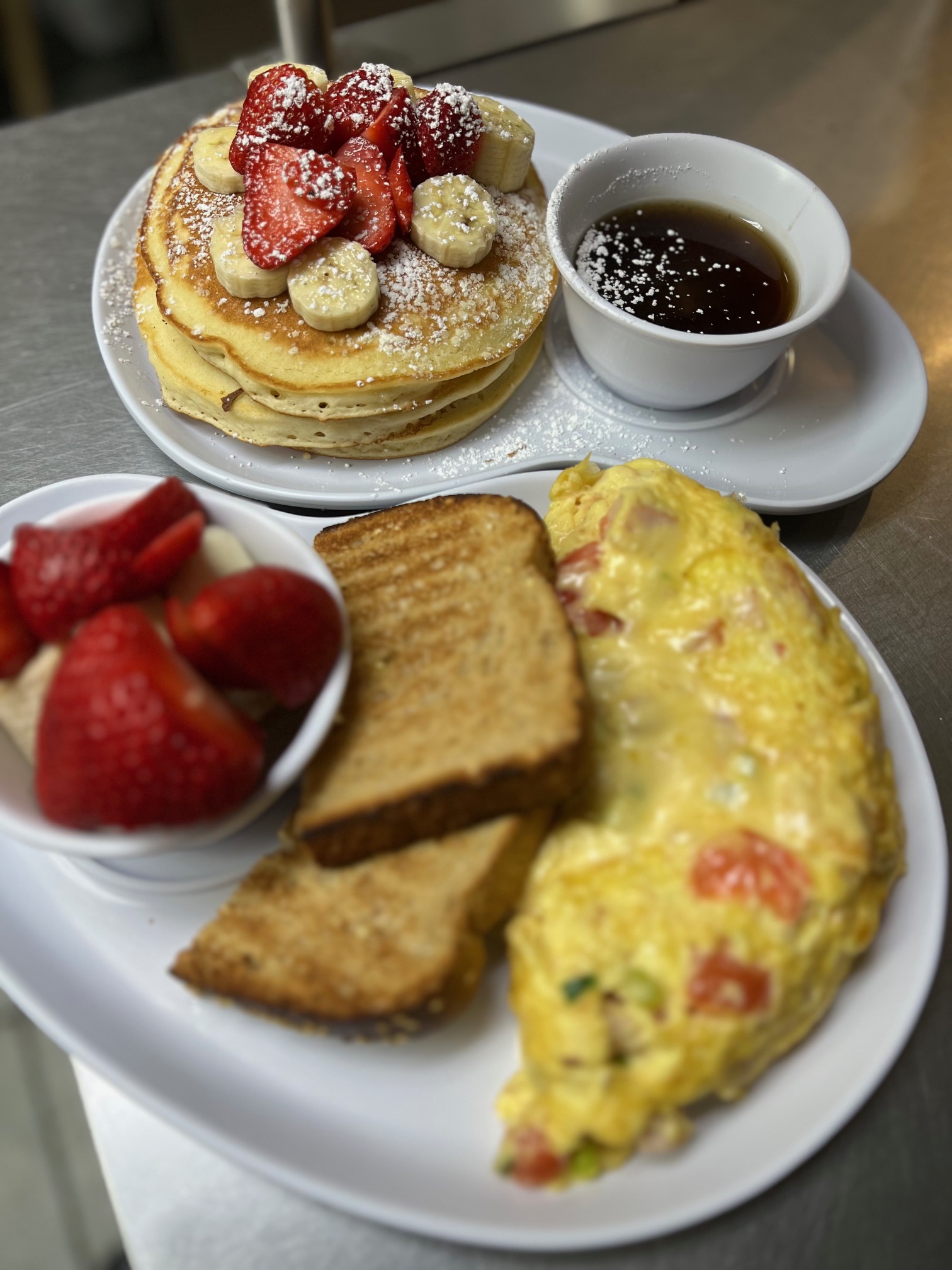 Pancakes, French toast and an omelet plate held up by a server