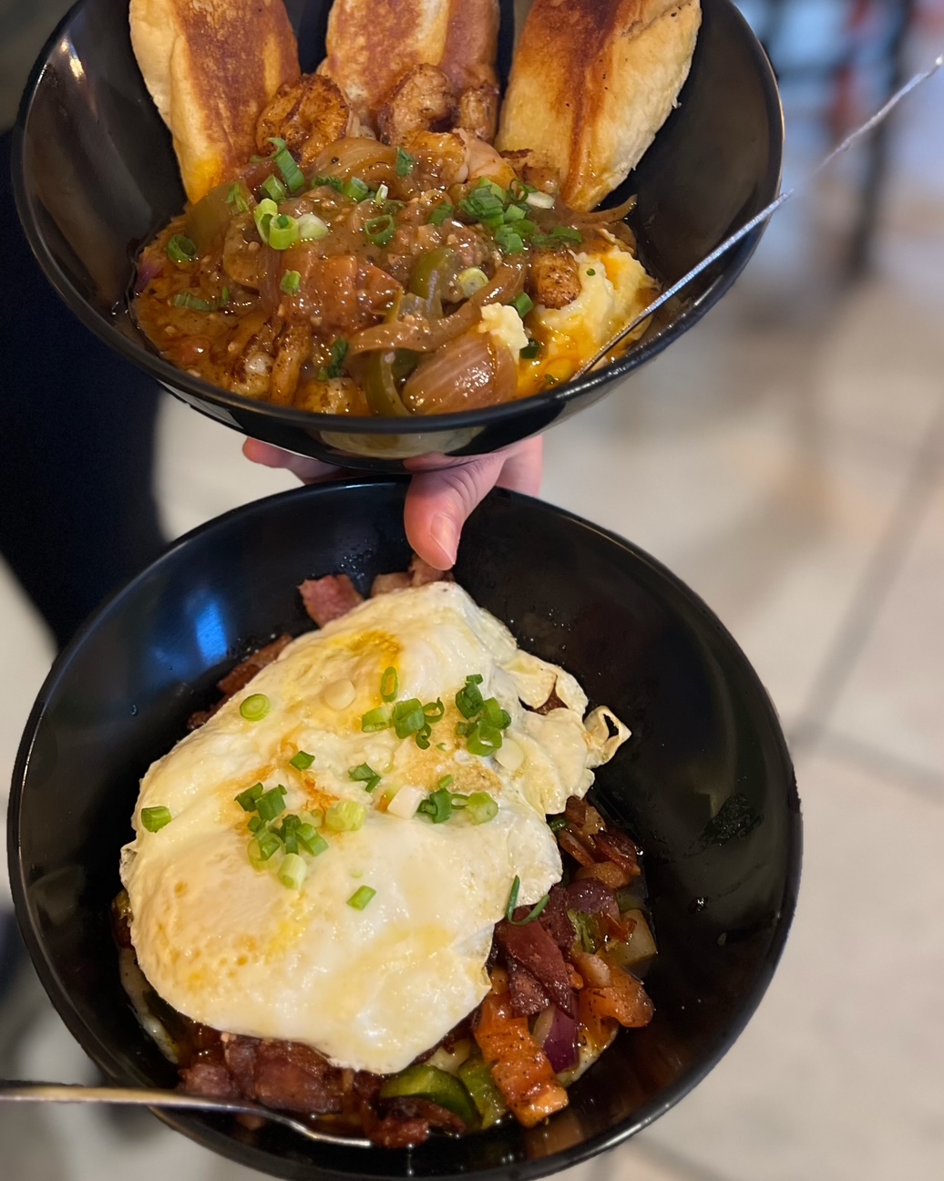 Stacked bowls of shrimp and grits and a bacon and egg hash