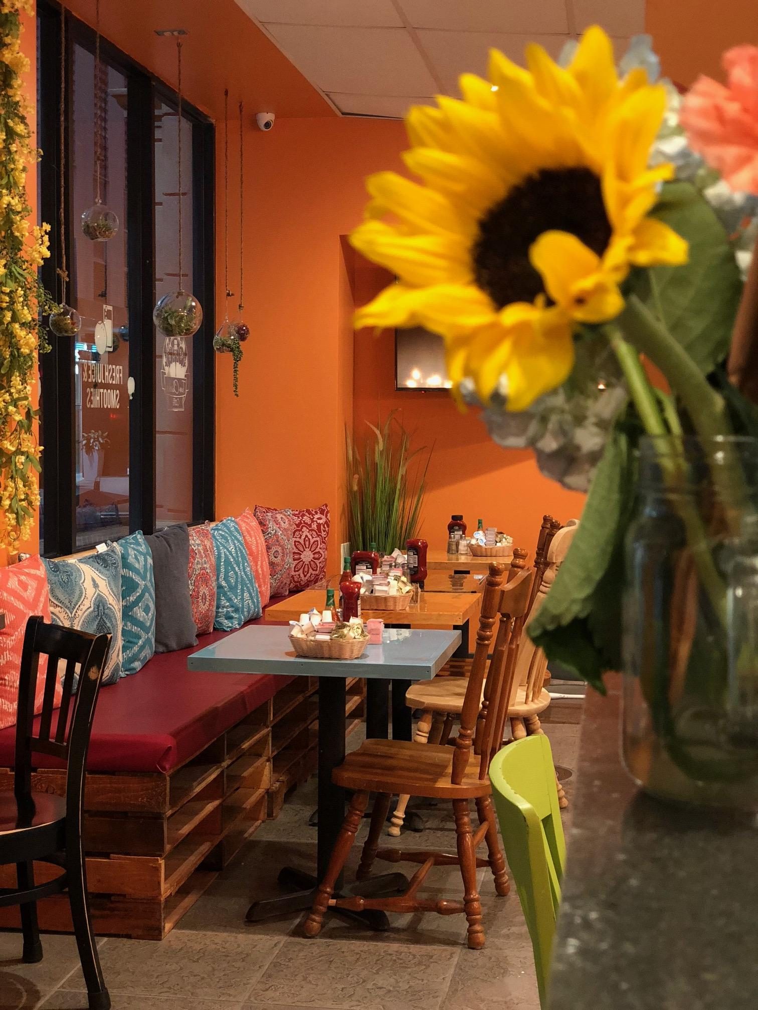 Cozy lounge corner with a sunflower, colorful throw pillows and a red banquette